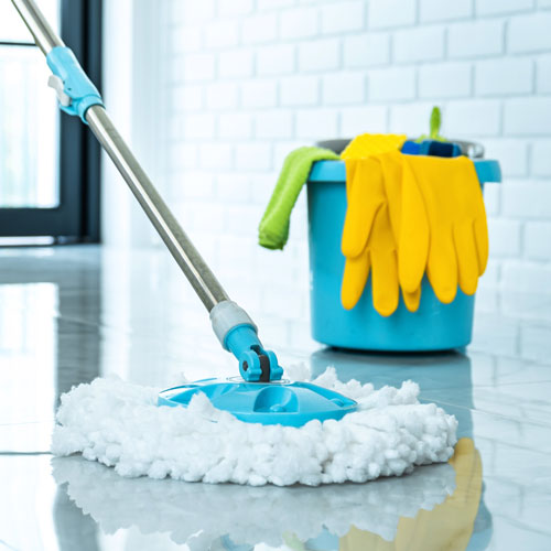 Reinigungsset mit blauem Eimer, gelben Handschuhen und Wischmopp auf glänzendem Boden – Symbol für professionelle Unterhaltsreinigung Offenbach.